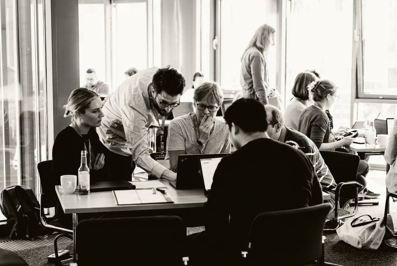 Teams arbeiten beim Hackathon an ihren Tischen